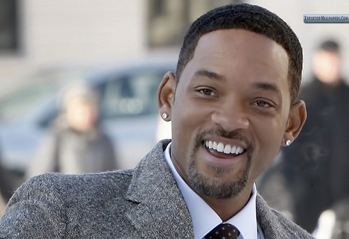 Actor Will Smith smiling happily to the camera in an grey suit