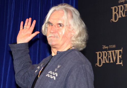 Billy Connolly waving in front of a backdrop written Disney Pixar Brave